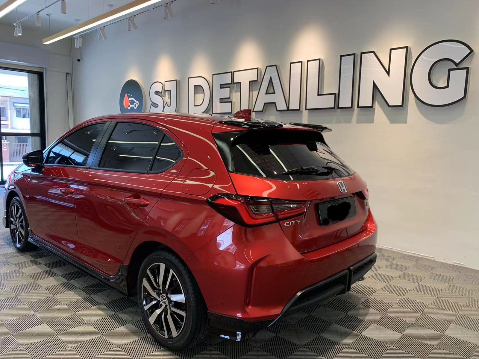 A red hatchback in the SJ Auto Detailing showroom