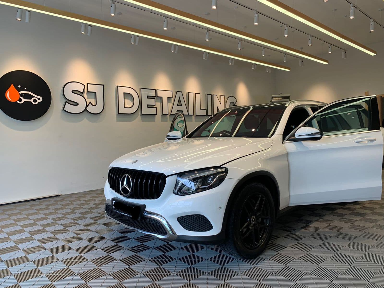 A white SUV inside the SJ Auto Detailing showroom
