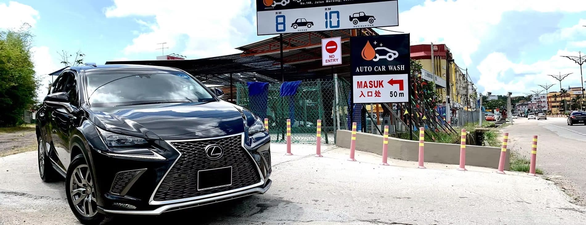 A black SUV parked in front of the SJ Auto Car Wash entrance signs on Jalan Mersing, Kluang